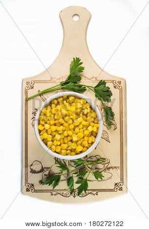 Corn grain in a plate on a cutting board. View from above.