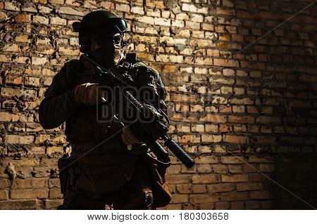 Special forces operator pointing weapon in the dark. Combat helmet, and bulletproof vest are on. Low key image, shadow soldier