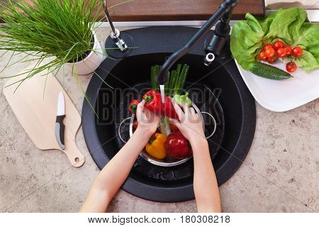 Washing vegetables to make a fresh salad - child hands scrubbing a pepper under the kitchen tap