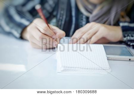 a man with a pencil in one hand is calculating his monthly expenses on smartphone