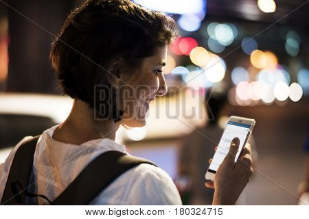 Woman using smart phone walking on street night time