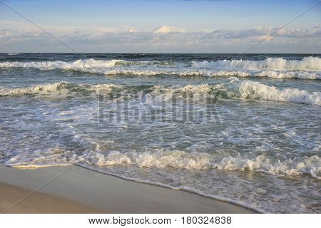 Breaking surf rolls onto pristine Florida beach at daybreak on a clear and colorful day.