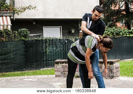 a guy helping a young girl with the heimlich desobstruction while she's choking
