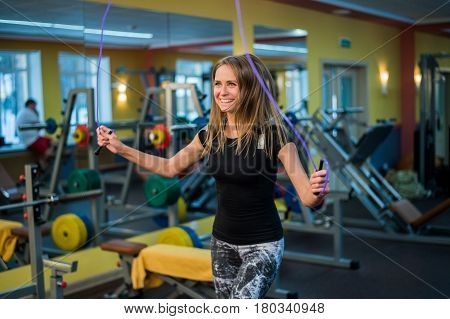 athletic young woman in sportswear exercising with skipping rope at gym