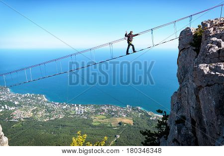 CRIMEA, RUSSIA - MAY 19, 2016: Tourist walking on rope bridge on the Mount Ai-Petri. Ai-Petri is one of the highest mountains in the Crimea and tourist attraction.