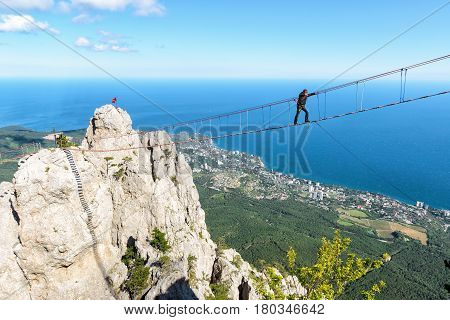 CRIMEA, RUSSIA - MAY 19, 2016: Tourist walking on rope bridge on the Mount Ai-Petri. Ai-Petri is one of the highest mountains in the Crimea and tourist attraction.