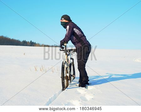 Biker Pushing Mountain Bike On Snow Drift. Freeze Sunny Winter Weather. Biker Is Pushing Bike In Dee