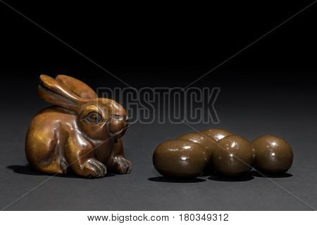 Easter bunny rabbit netsuke with mini Easter eggs. Carved wooden rabbit netsuke looking very much like the Easter bunny next to some mini chocolate truffle Easter eggs