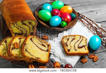 Easter card. Easter treat cozonac painted chicken and quail eggs. Easter willow pecans nuts. Rustic style gray wood background.