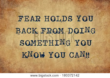 Inspiring motivation quote with typewriter text fear holds you back from doing something you know you can. Distressed Old Paper with Typing image.