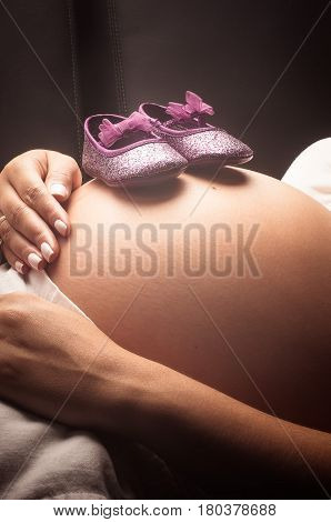 Baby shoes over the belly of a pregnant woman