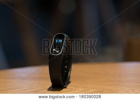 A clock of fitness smart band device on wooden table