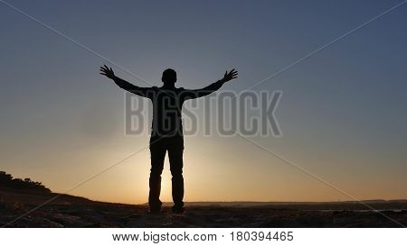 freedom. Man stands on cliff sunset silhouette hand in lifestyle the sides
