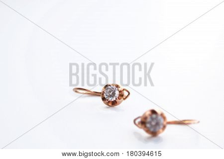 Gold earrings with white gem on white background