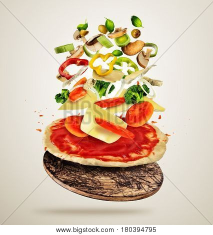 Concept of flying ingredients with pizza dough, isolated on creamy background. Food preparation, fresh meal ready for cooking