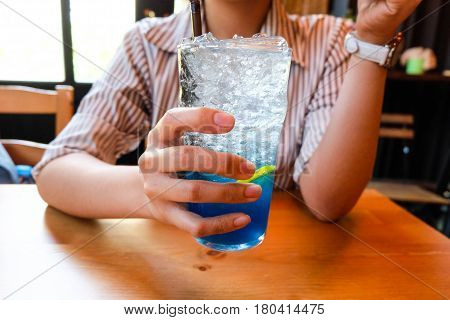Young Woman Handle  Glass Of Splash Blue Lemon Juice Soda On The Wood Table, Suumer And Fresh Concep