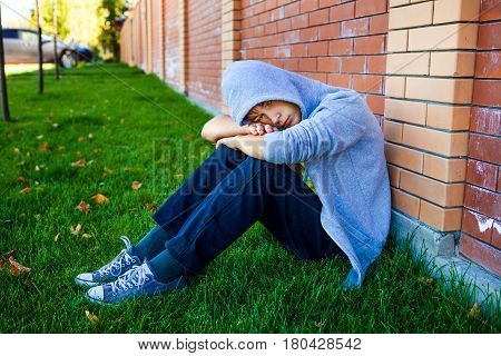 Sad Teenager sit by the Brick Wall outdoor