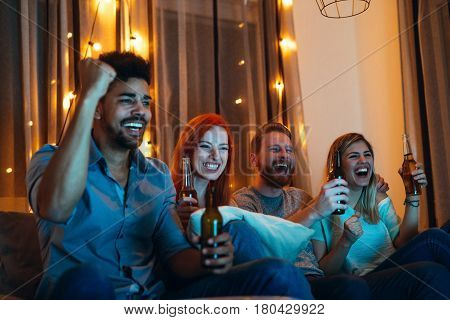 Shot of four cheerful friends enjoying watching a movie at home.