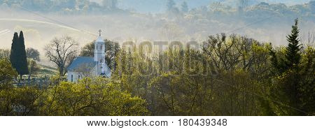 Church photographyed wide angle amongst the trees and fog sitting behind