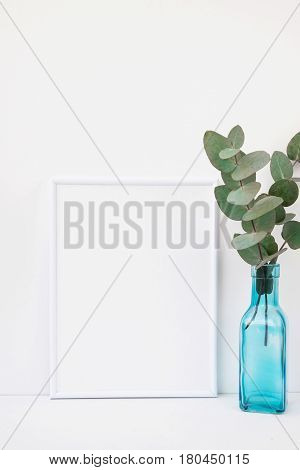 Frame mockup on white background green eucalyptus branch in blue glass bottle copyspace for text styled image for social media marketing