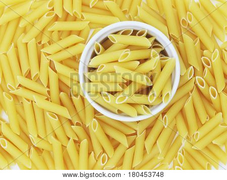 Organic raw penne pasta in the blow on white background
