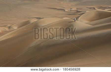 young man walking in sand dunes in Liwa desert in Abu Dhabi