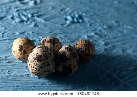 pile of quail eggs against blue background close up