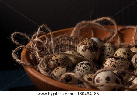 quail eggs in wooden bowl isolated on blue background. close up