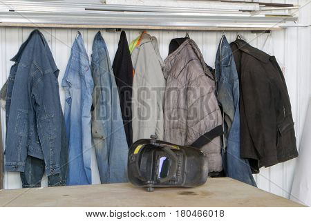 Dirty work clothes hanging on a hanger against a white wall. Waiting for the wash.