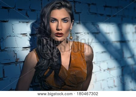 fashion portrait of young pretty woman posing at wall, wearing stylish bright orange dress