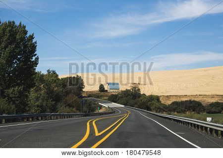Barn building on farmland in rural countryside. Driver's point of view on highway.