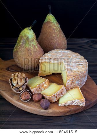 Soft washed-rind cheese walnut hazelnuts and pears on the wooden board