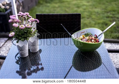 Delicious fresh healthy salad in a green bowl with salad spoon food standing on a the table with flowers