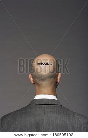 Rear view of a bald businessman against gray background with text saying missing