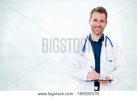 Handsome Young Smiling Doctor With Clipboard