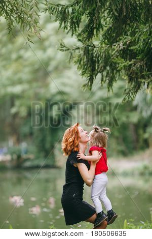 mom and little daughter walking in green summer park