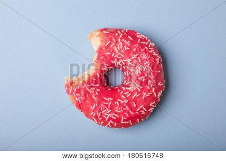 one bite tasty donut with pink glaze isolated on blue background