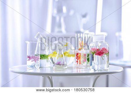 Beautiful composition with perfume samples and flowers on table