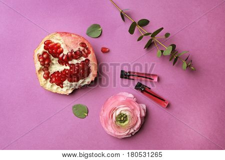 Beautiful composition with perfume samples,  pomegranate and flower on color background