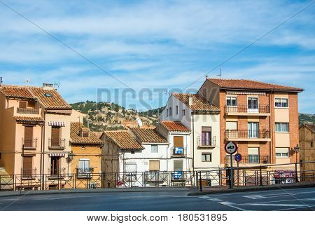 TERUEL SPAIN - FEBRUARY 01 2016: Houses with tile roofs near the road and clay hills at the background street of Teruel a medieval historical town at Aragon Spain.