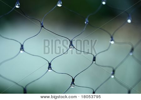 Cerca de gotas de hielo de fusión en la valla de alambre