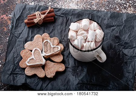 hot cup of coffee with biscuits a heart and marshmallows cinnamon sticks