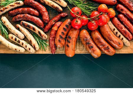 Grilled sausages on a board lighten up by summer sunny warm light space for a text view from above
