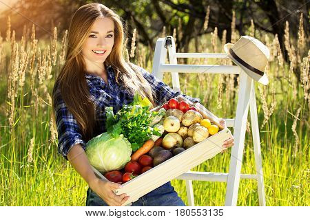 Pretty And Young Smiling Girl Keeping Wooden Box Full Of Vegetables. Summer Harvest.