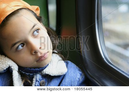 一个年轻的女孩盯着窗外从行驶的火车，在她小小的世界失去了