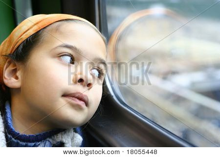 一个年轻的女孩盯着窗外从行驶的火车，在她小小的世界失去了