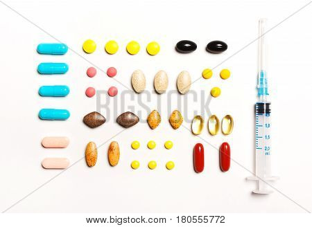 multi-colored tablets and prick vitamins dietary supplements in a row on a white background. View from above flat