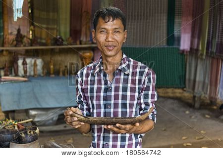 Siem Reap, Cambodia - January 03, 2017: An artisan at the palm sugar producers village showing one of his wooden work