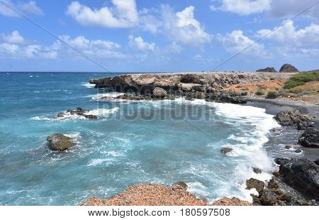 The ocean swirling off the coast of Aruba's black sand stone beach.