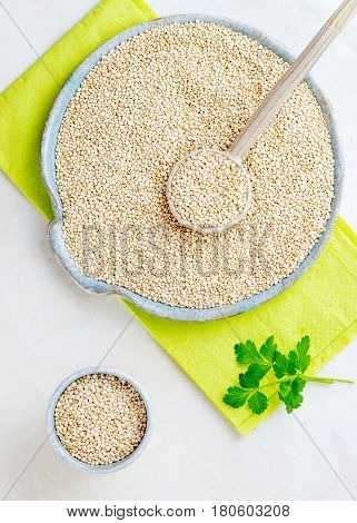Vertical image of bio quinoa in a large ceramic dish with a spoon and a small bowl to the left copy space available.